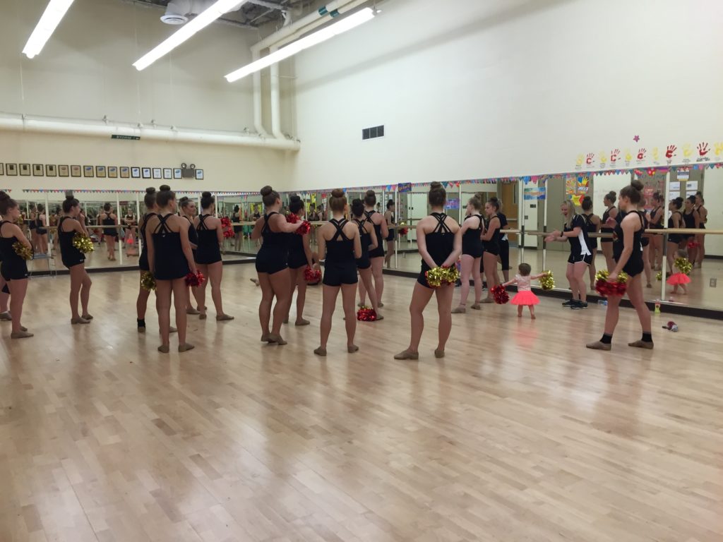A future dancer listens in as Batavia Varsity gets feedback from Coach Fuqua