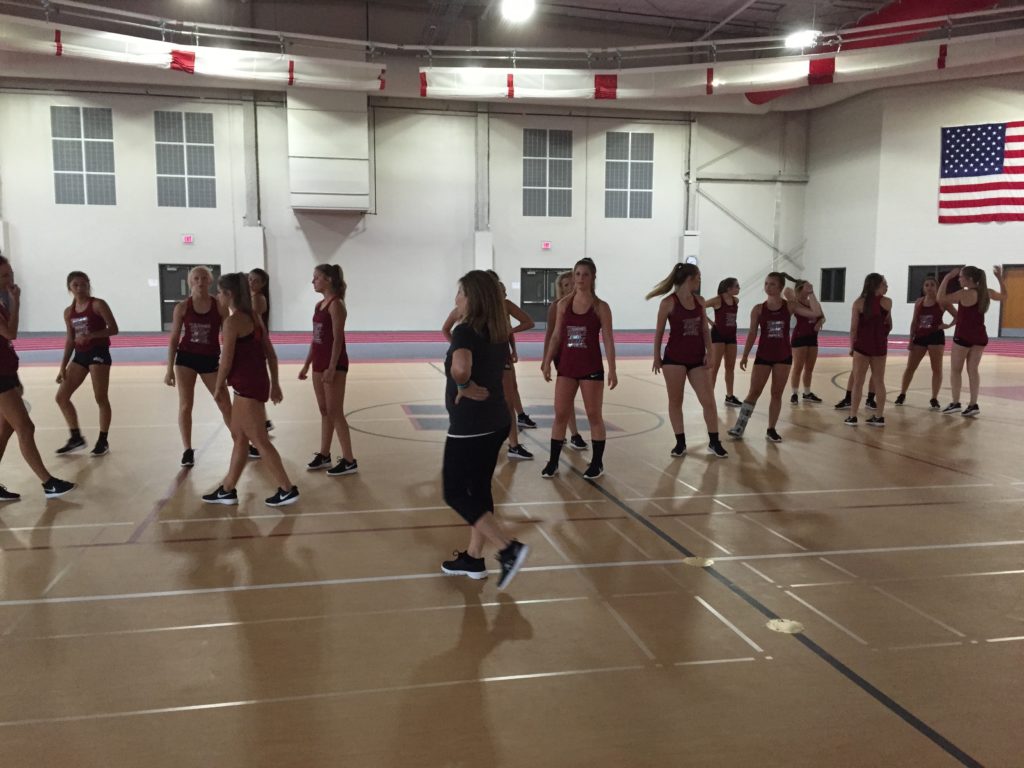 Coach Amling and her dancers on the red floor of their new fieldhouse